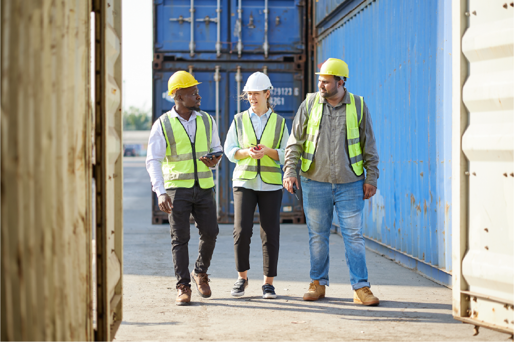 group of workers walking and talking about work next to containers 